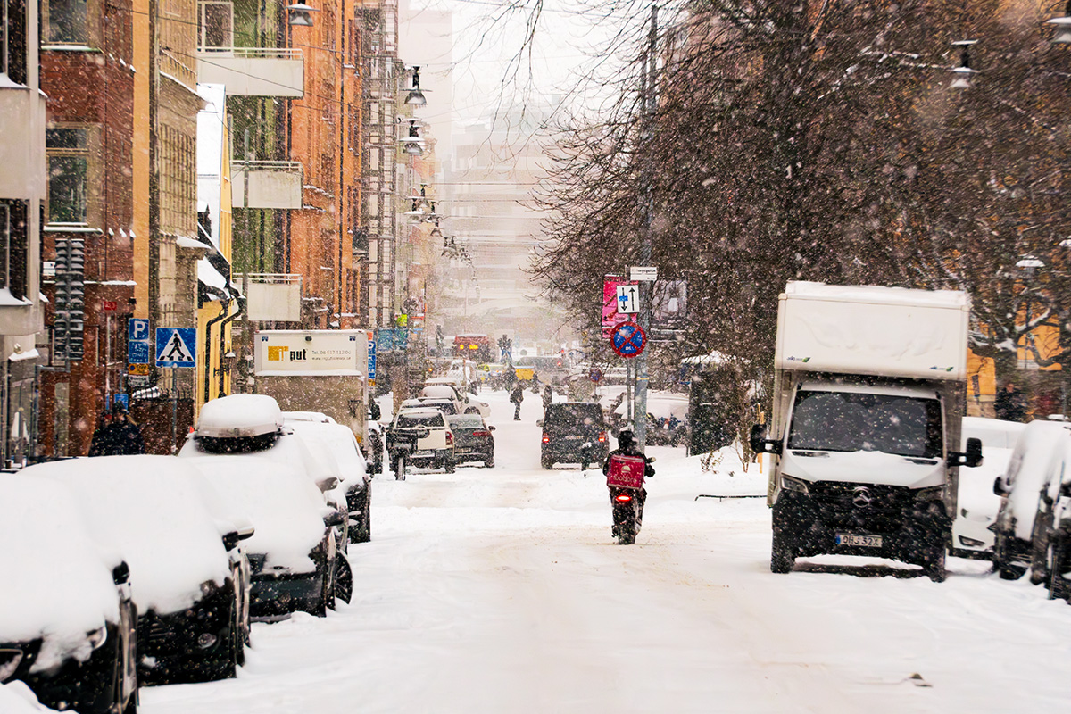 Foodorabud på moped åker på snöig innerstadsgata i Stockholm