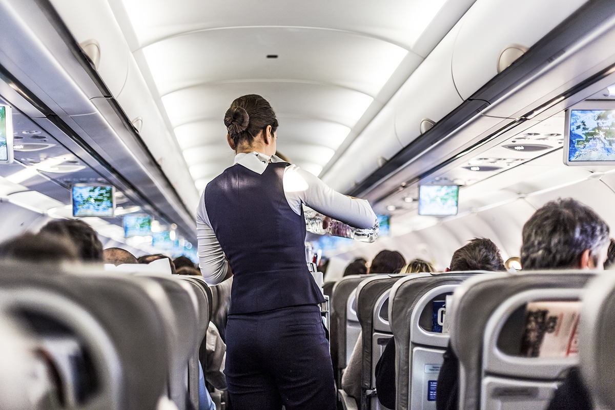 Flygvärdinna i mittgången på ett passagerarplan